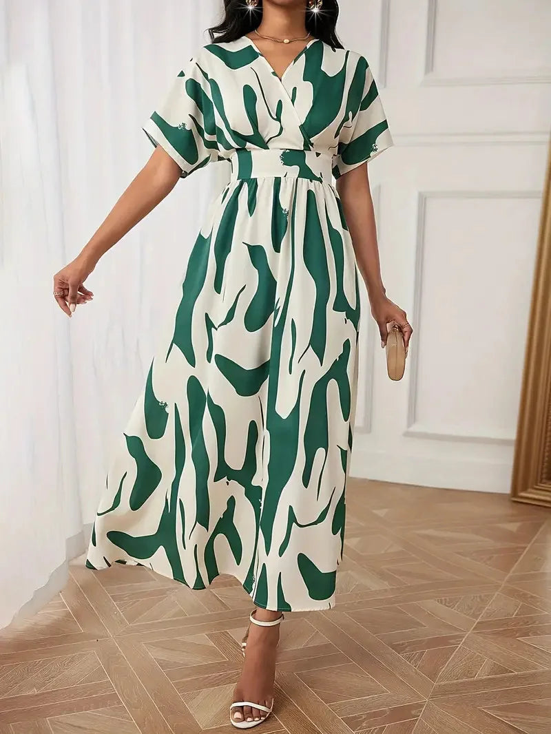 Woman wearing a green and white patterned dress in a room with wooden flooring.