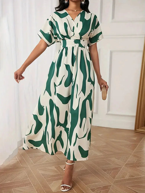 Woman wearing a green and white patterned dress in a room with wooden flooring.