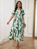 Woman wearing a green and white patterned dress in a room with white walls and wooden flooring.
