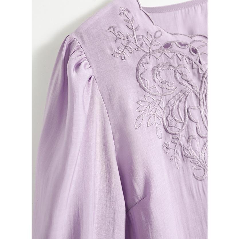 Close-up of a lavender purple blouse with gathered puff sleeves and intricate floral embroidery on the chest.