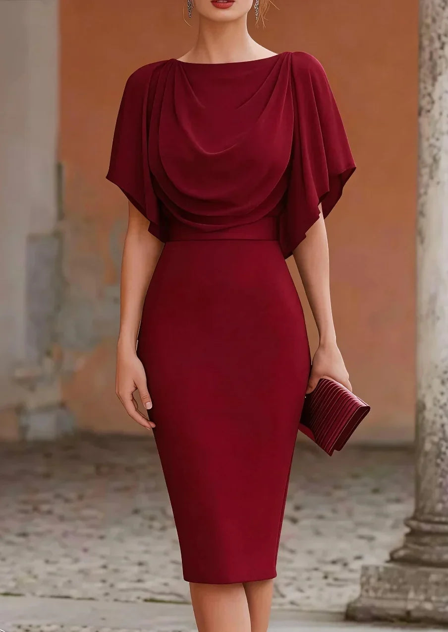 Woman wearing a burgundy dress with a draped neckline in an outdoor setting.